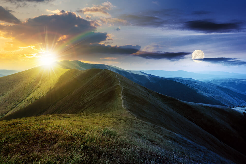 山の上に見える太陽と月